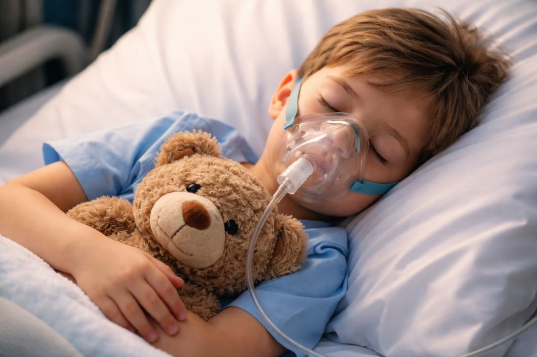 Παιδί με μάσκα οξυγόνου στο νοσοκομείο αγκαλιά με αρκουδάκι – κυστική ίνωση στα παιδιά και αναπνευστικά συμπτώματα